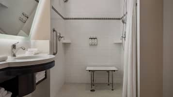 A modern bathroom with a white sink, mirror, and shower.