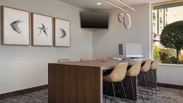 Een vergaderruimte met een lange tafel, zes stoelen, een flatscreen-tv en ingekaderde kunstwerken aan de muur.