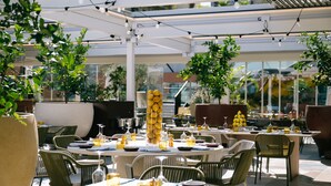 An outdoor dining area with round tables, chairs, and a decorative centerpiece of lemons. - voco Malta by IHG (St. Julian's)