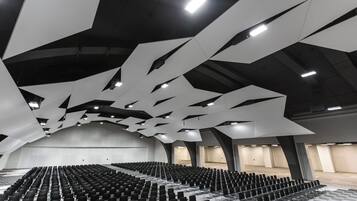 Un salón amplio con filas de sillas y un diseño moderno del techo.