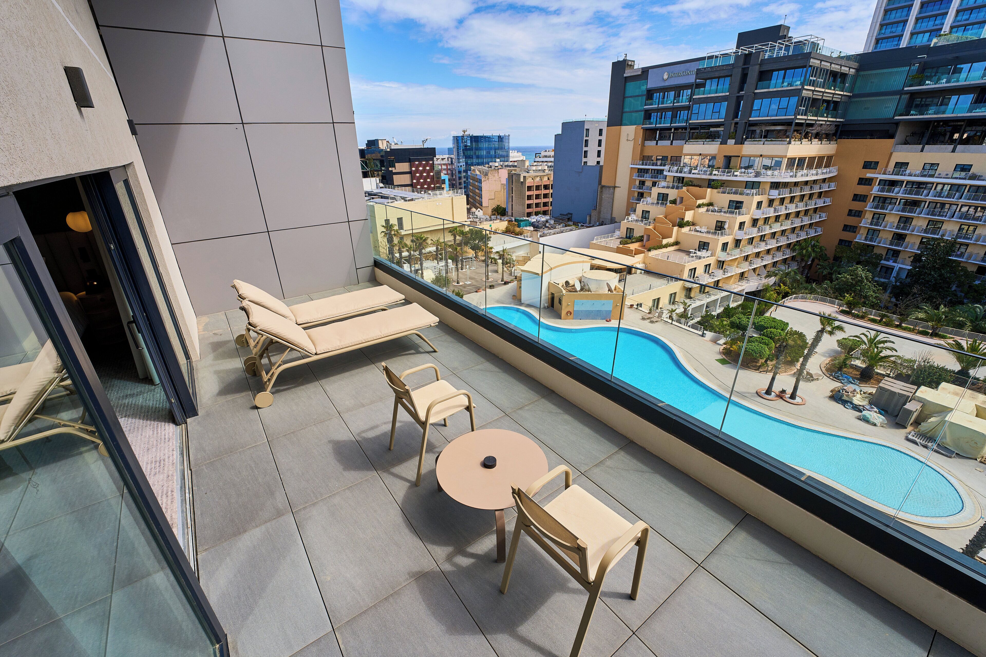 Un balcon avec une piscine, des chaises longues et une table.
