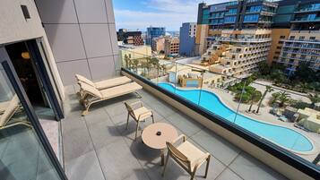 Un balcon avec une piscine, des chaises longues et une table.