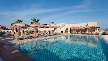 Una piscina cubierta, una piscina al aire libre, sombrillas, tumbonas