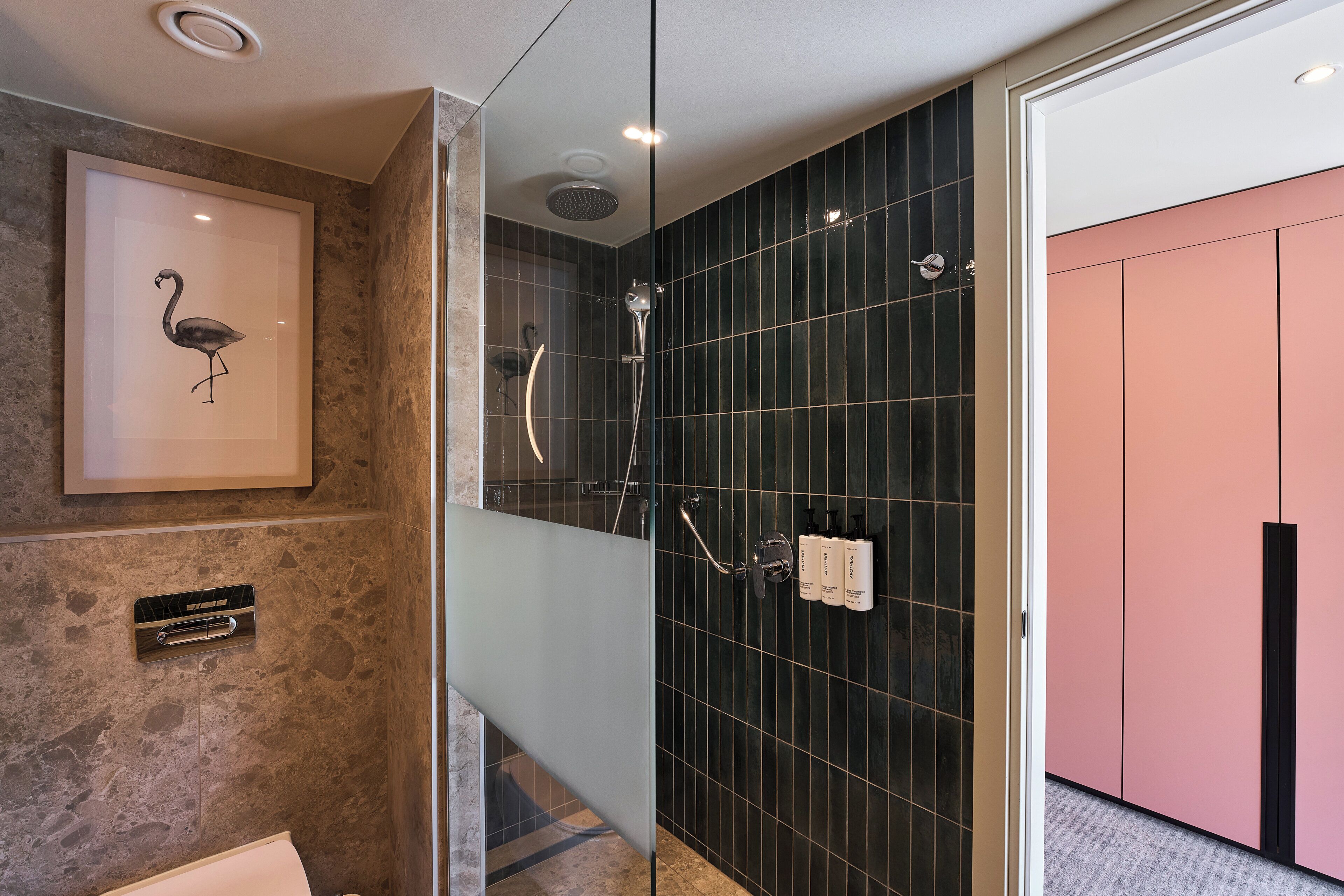 A modern bathroom with a glass-enclosed shower, a framed artwork on the wall, and a vanity with a marble-like texture.