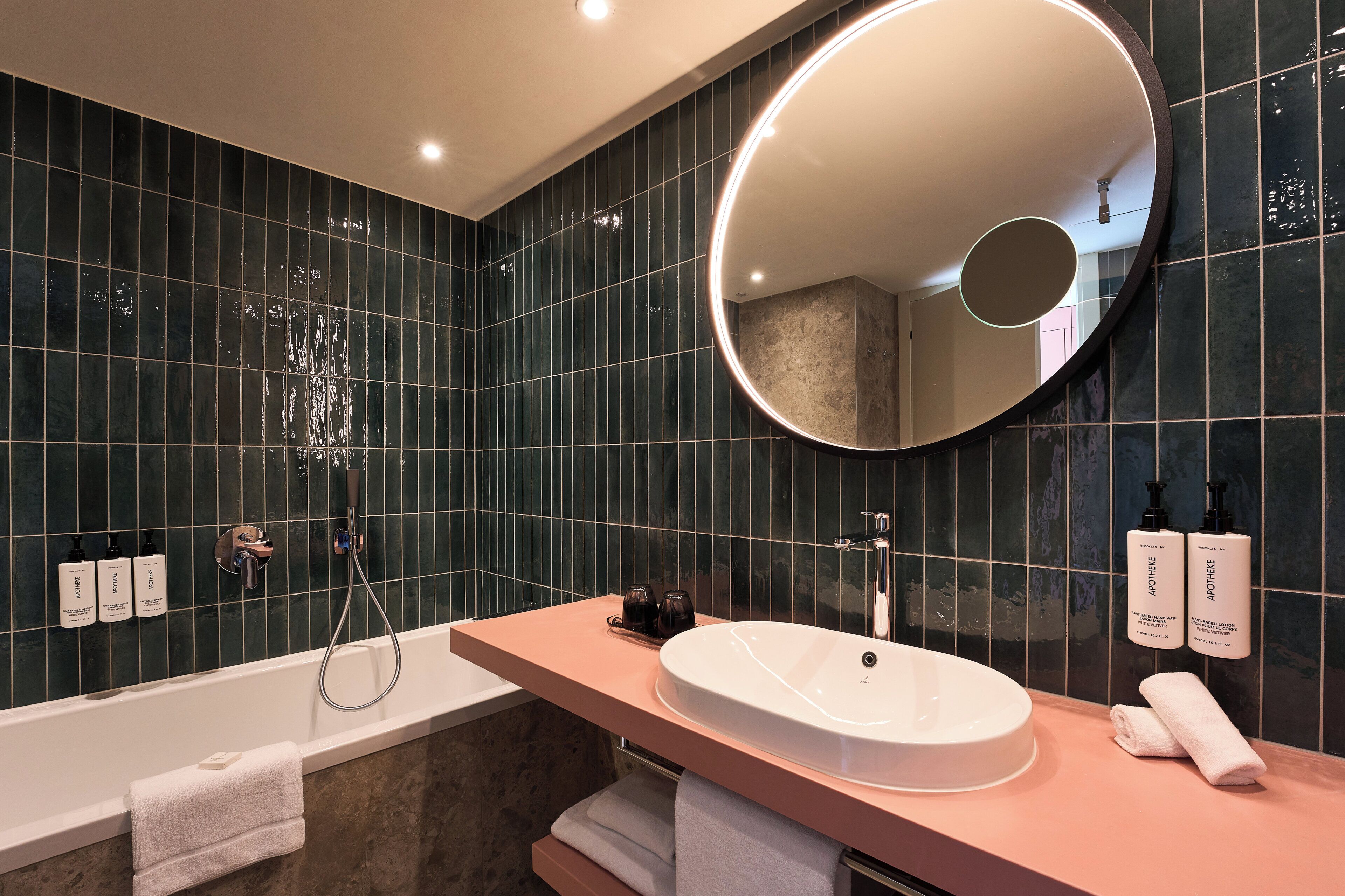 Un baño moderno con bañera, un espejo grande y un lavamanos.