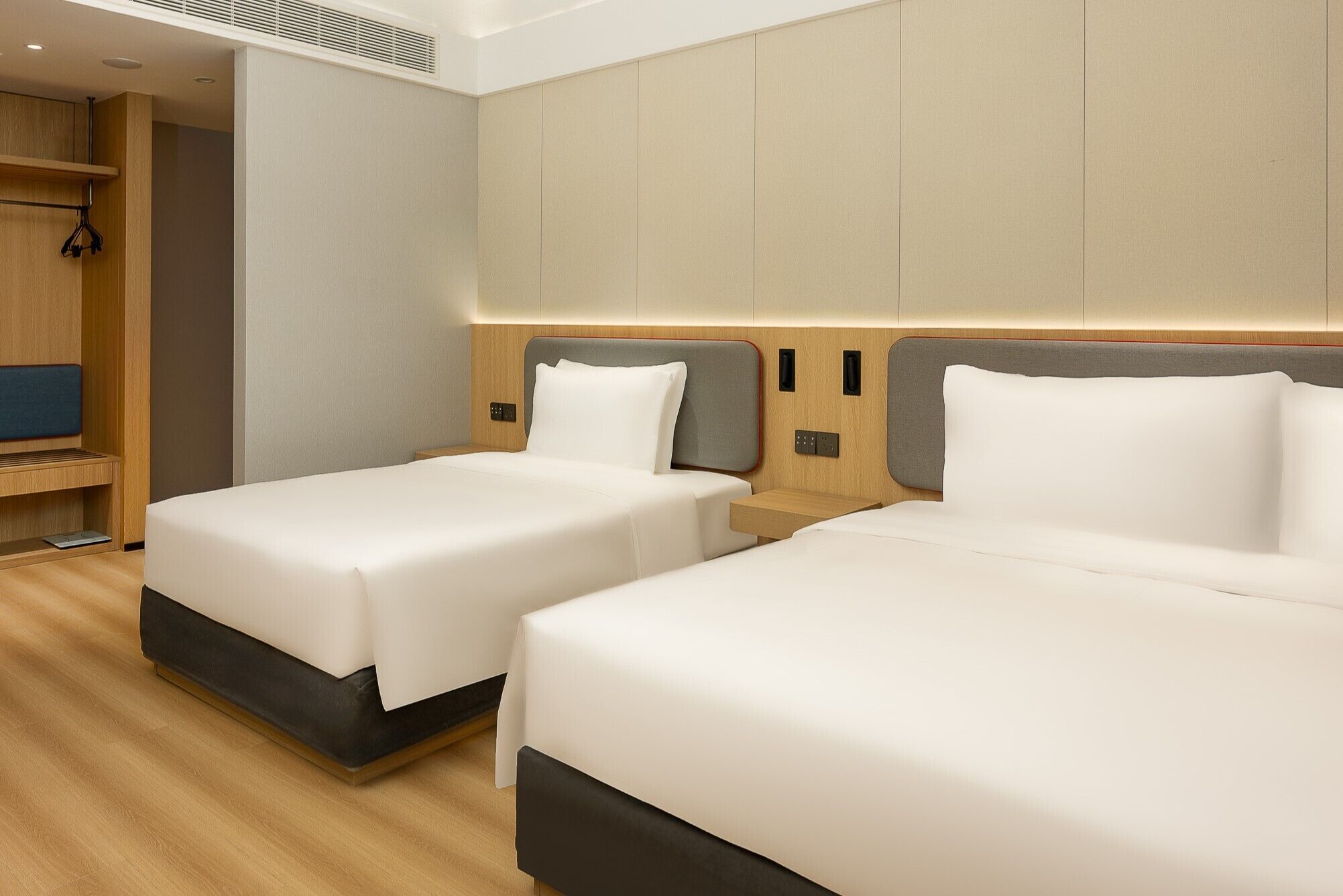 Two single beds with wooden headboards and a built-in shelf unit to the left.