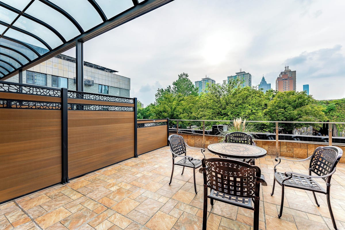 A rooftop terrace with a glass enclosure, outdoor seating, and a cityscape view.