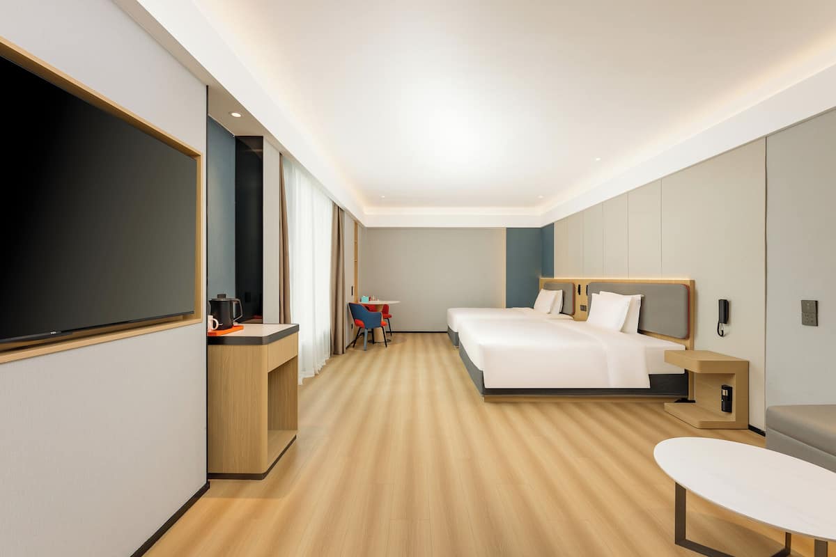 A modern hotel room with a large bed, a desk, a chair, and a TV.