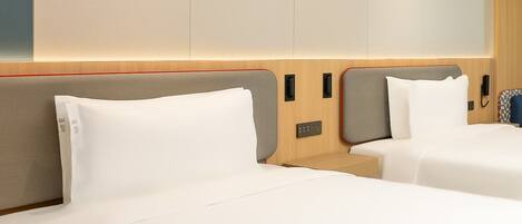 Habitación de hotel con dos camas, cabecero de madera, mesita de noche y teléfono en la pared.