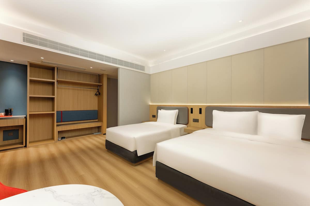 A hotel room with two beds, a desk, and a wardrobe.