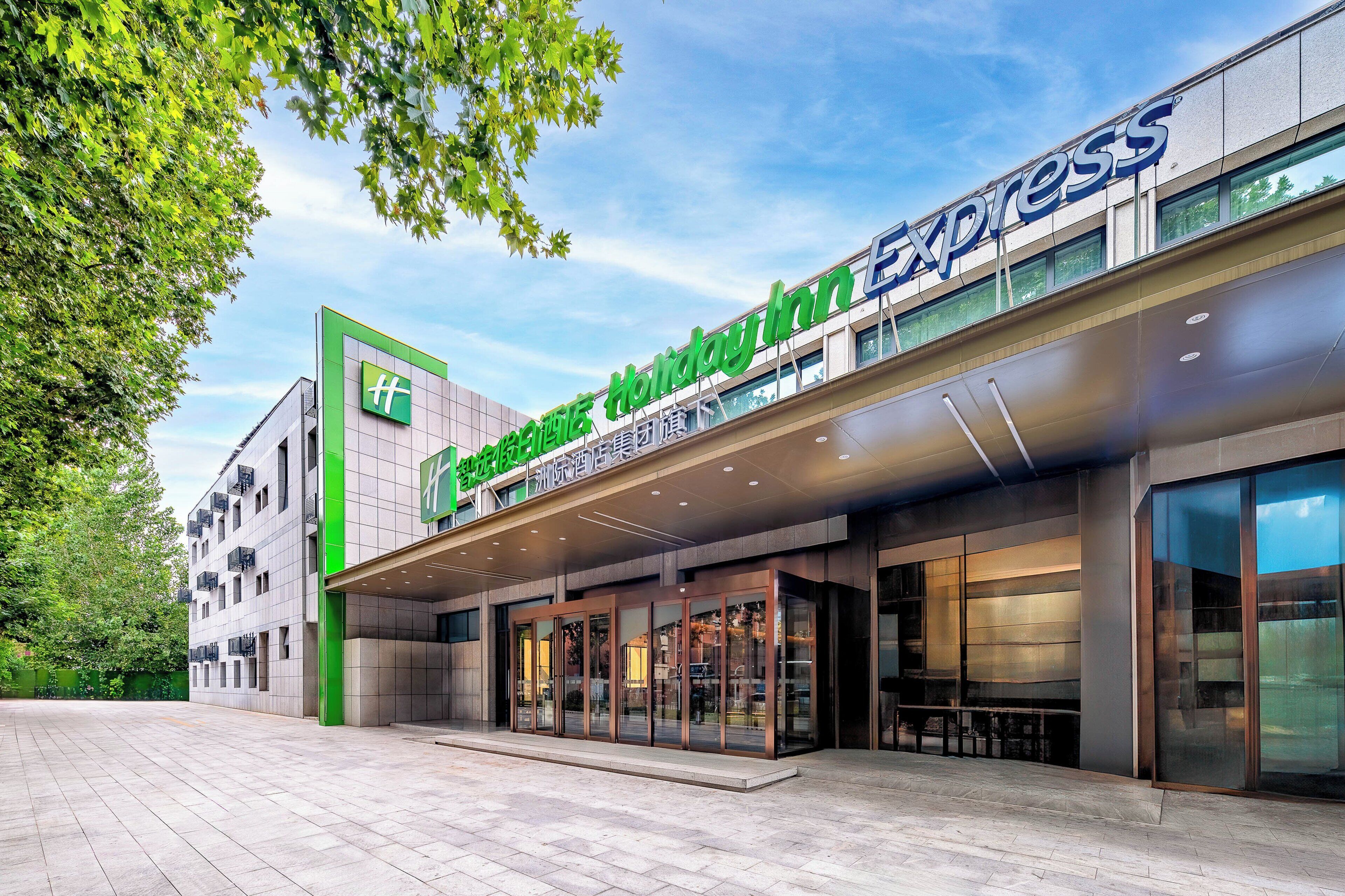 A Holiday Inn Express hotel with a modern facade, large glass entrance, and a spacious outdoor area.