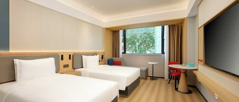 A hotel room with two beds, a small table, a TV, and a window with curtains.