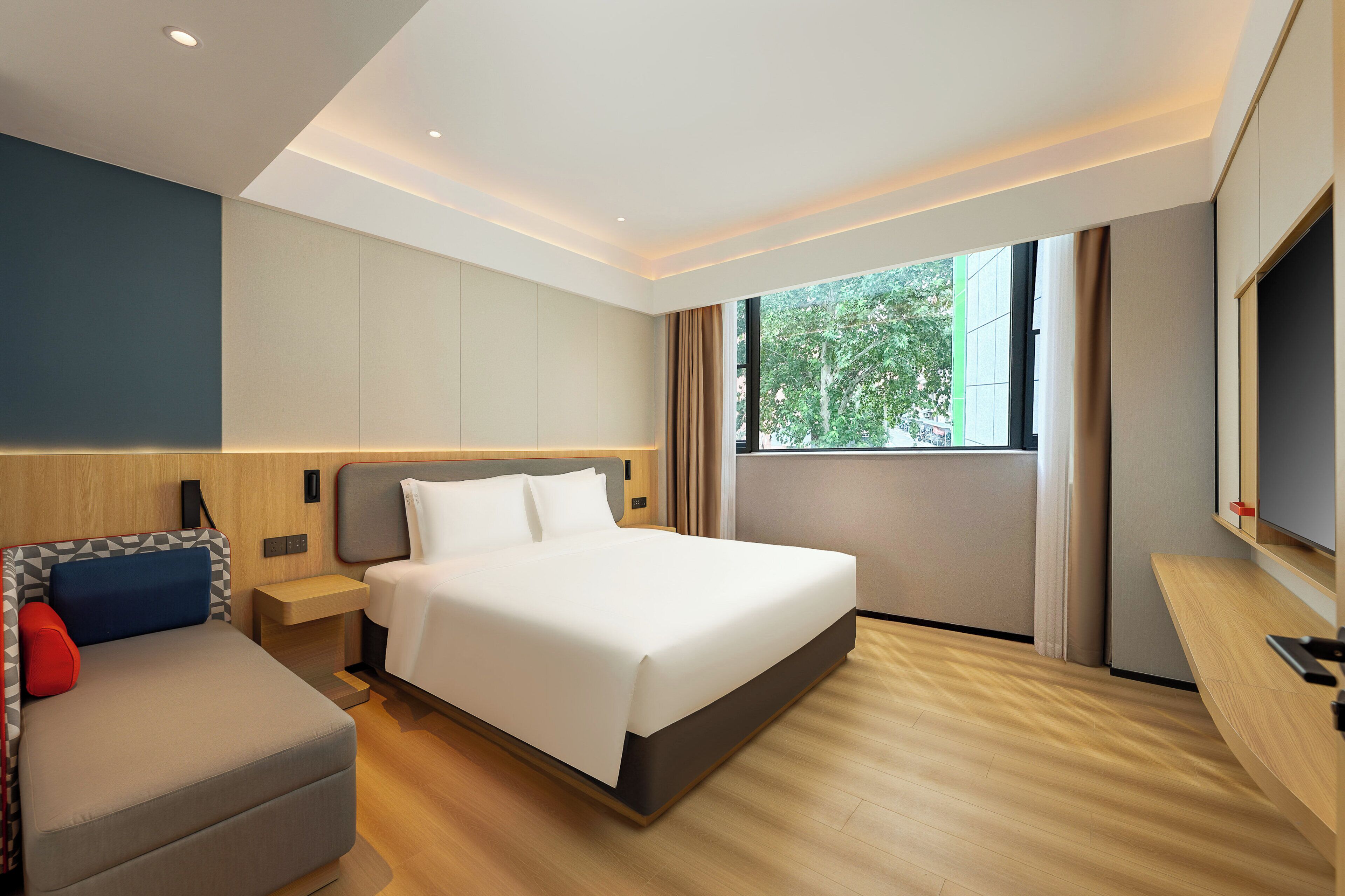 Una habitación de hotel moderna con una cama grande, un sofá, un televisor y una ventana con cortinas.