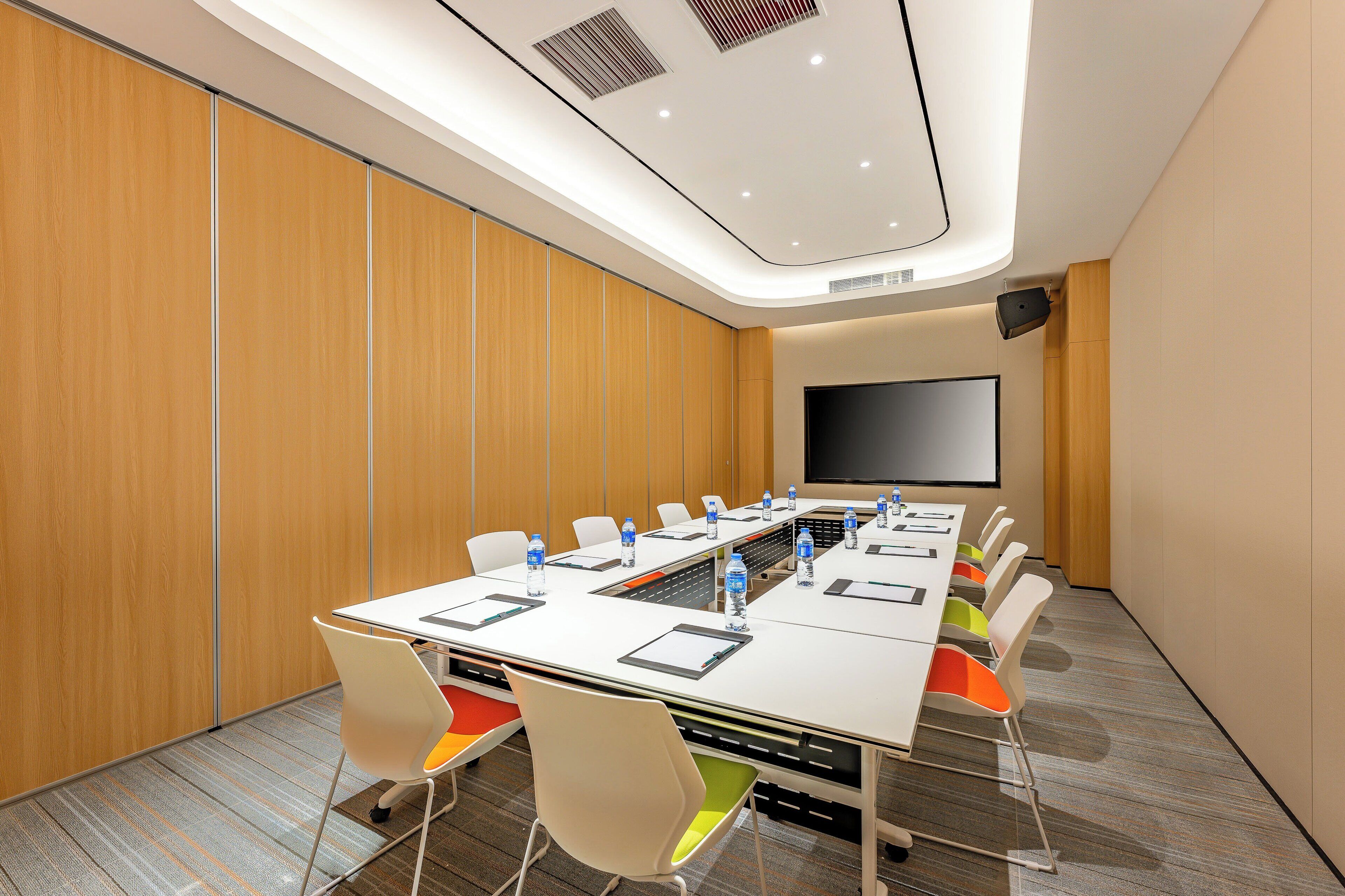 A conference room with a long table, chairs, a projector screen, and a whiteboard.