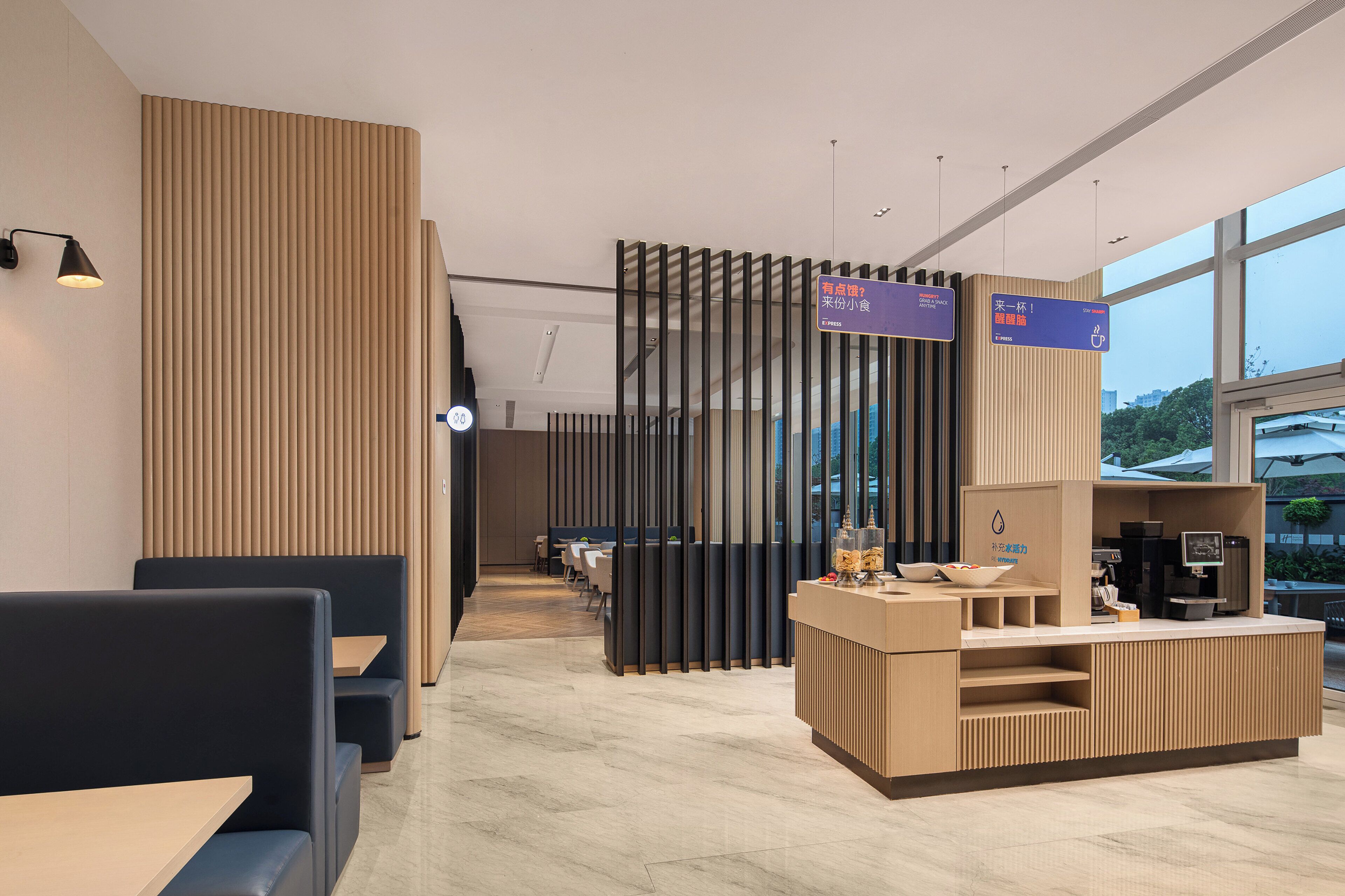 A modern restaurant with booths and a counter. There are signs indicating directions and a coffee machine.