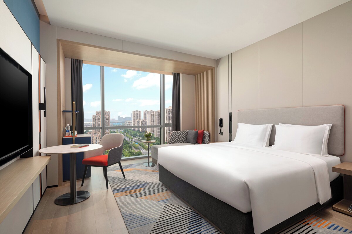 Een moderne hotelkamer met een groot bed, een bureau, een stoel en een televisie.