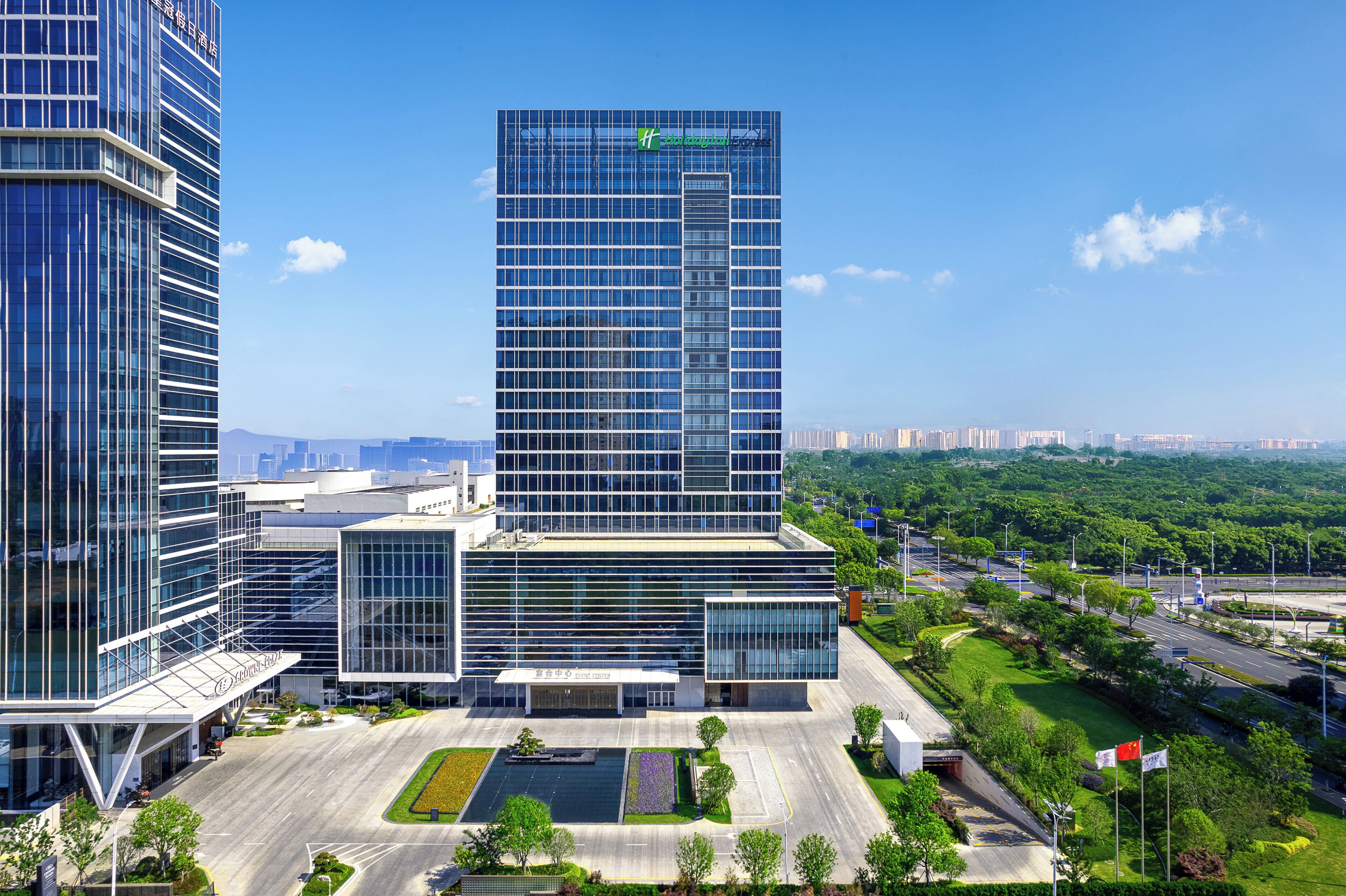 A modern hotel with a glass facade, a central courtyard, and a view of the surrounding cityscape.