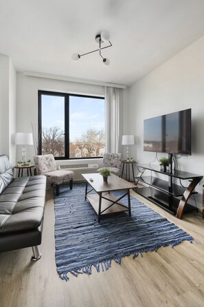 A modern living room with a sofa, armchairs, a coffee table, and a TV. - Nice Studio Close to EWR n4mh (Elizabeth)