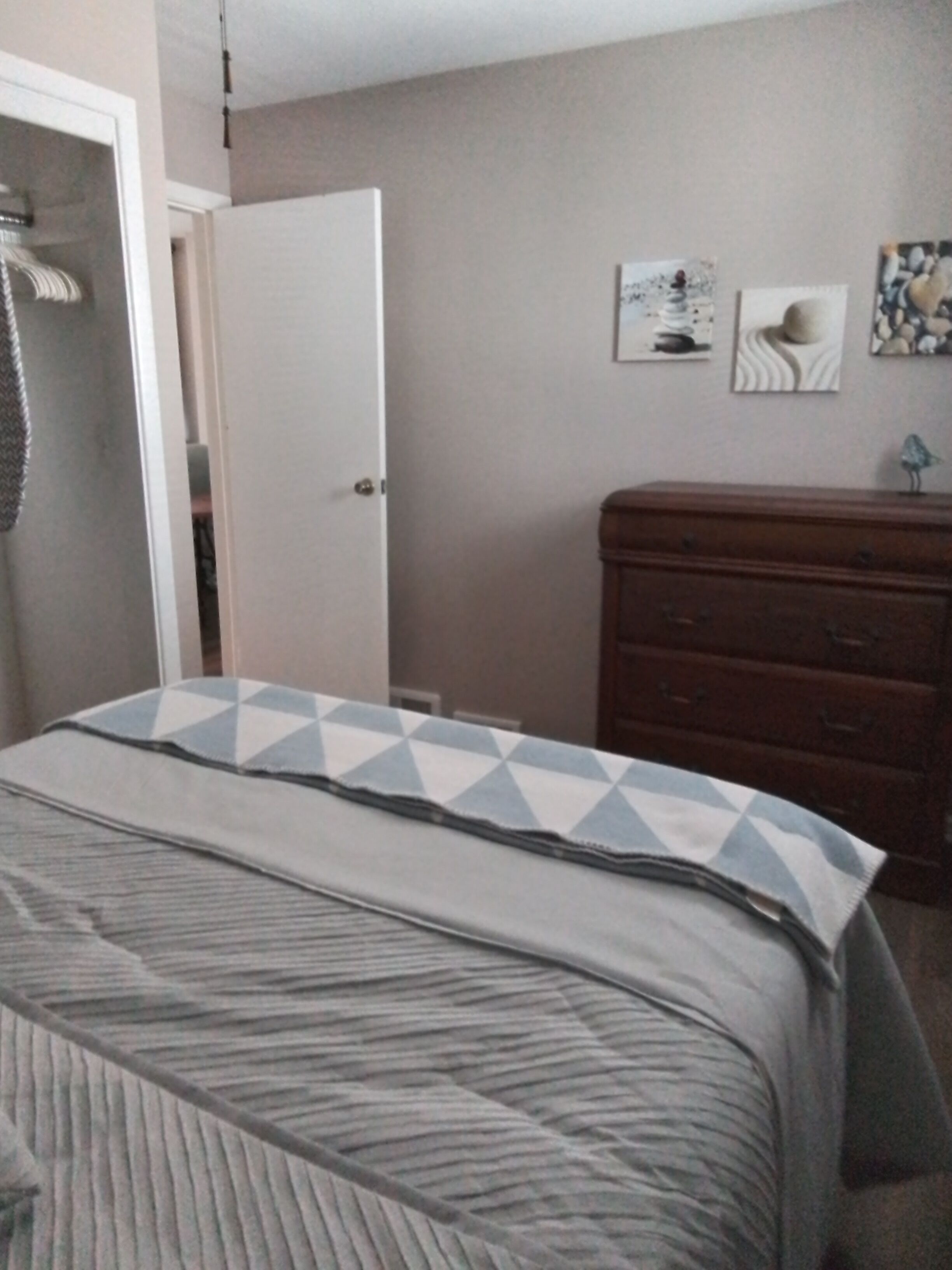 A bedroom with a bed, a dresser, and a door.