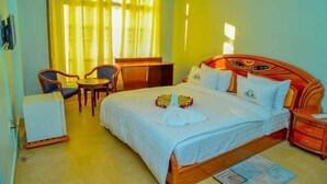 A hotel room with a bed, a desk, a chair, and a small table.
