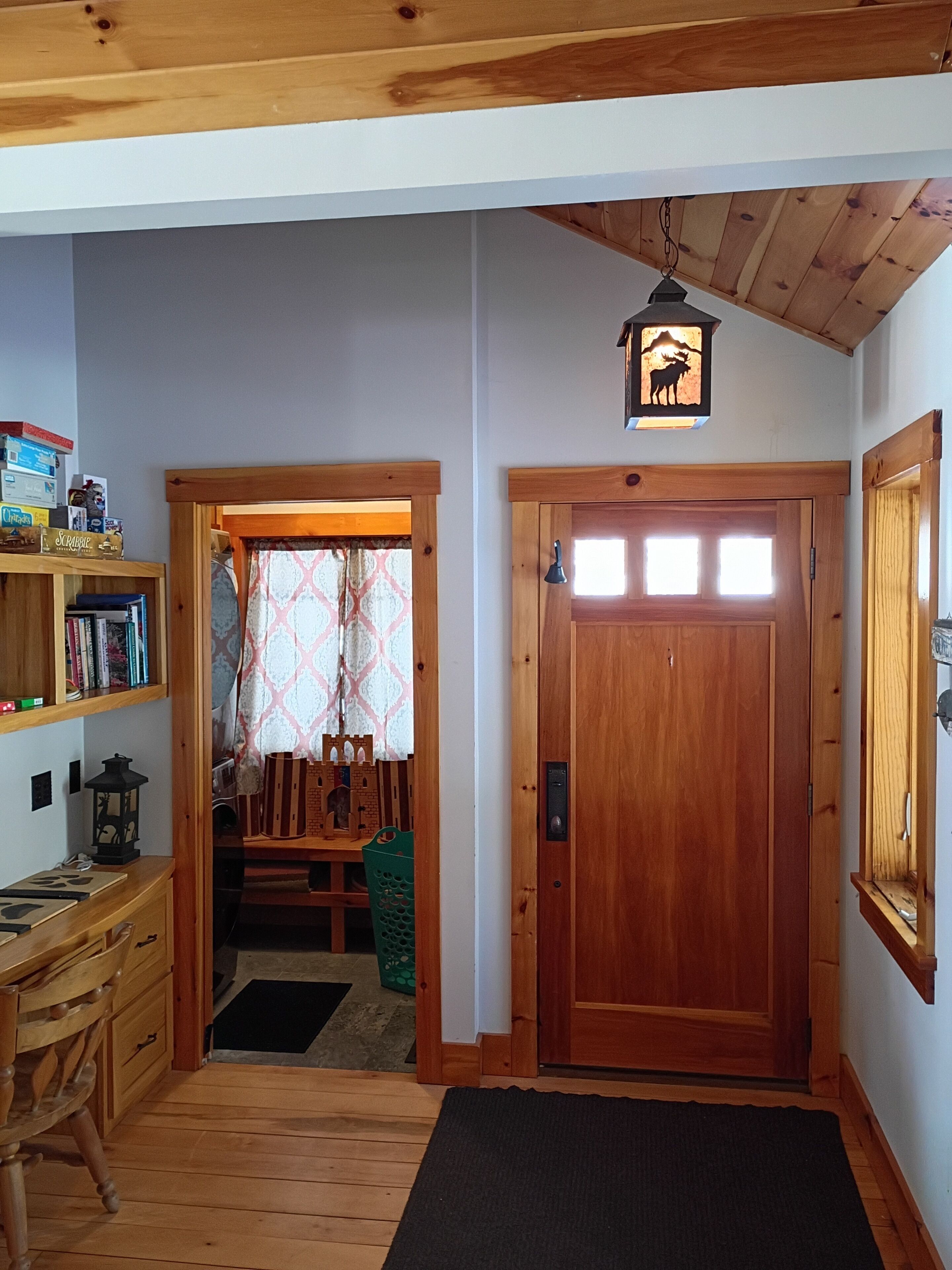 Un intérieur en bois comprenant un bureau, une bibliothèque et une porte avec un luminaire.