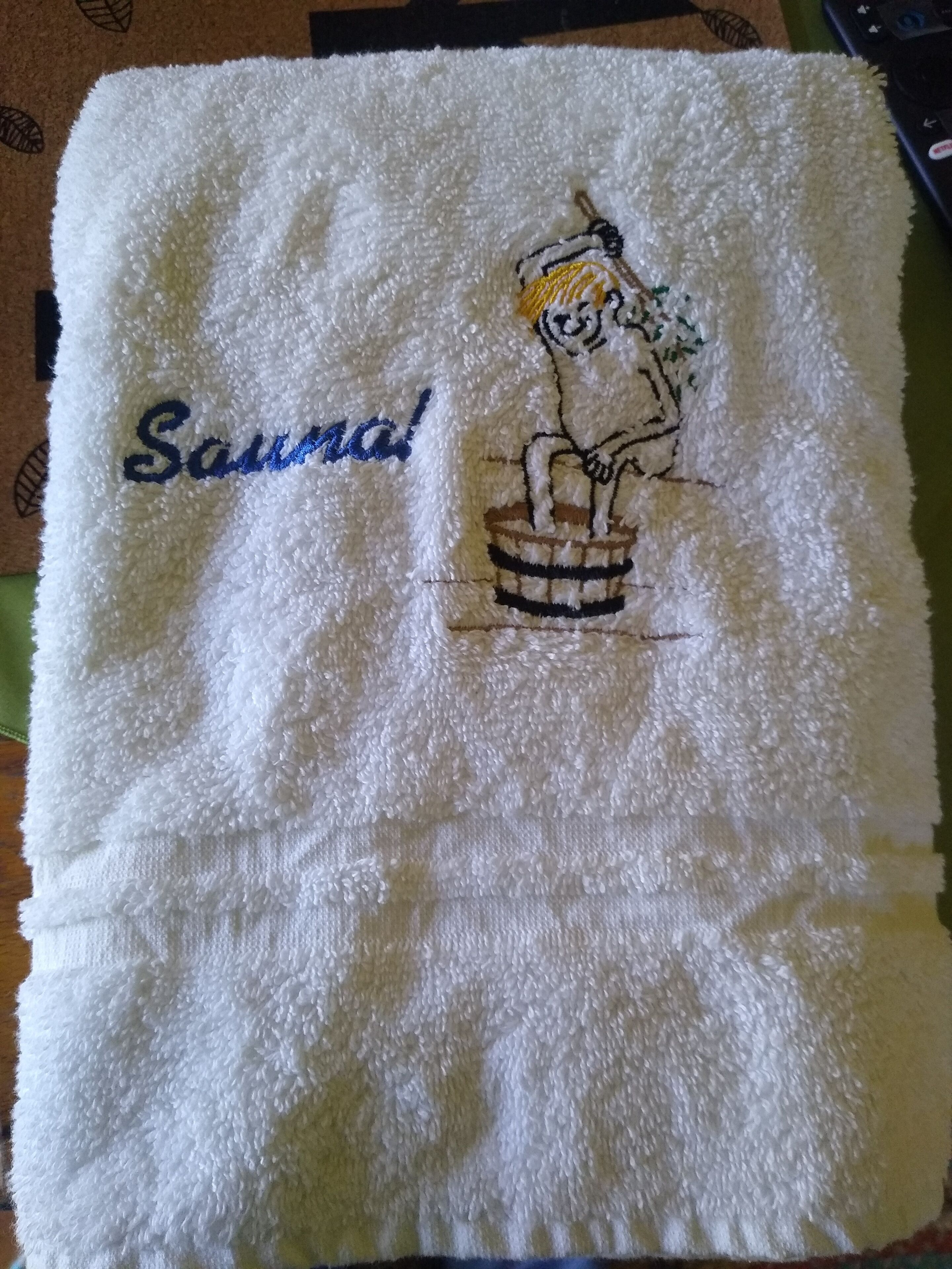 Un asciugamano bianco con un personaggio dei cartoni animati e il nome "Saudade" ricamato.