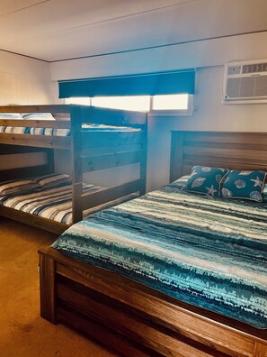 A room with bunk beds, a wooden headboard, a window with blinds, and an air conditioning unit. -  Spacious ocean front 1 bedroom condo sleeps 6, located in mid town Ocean City (Ocean City)