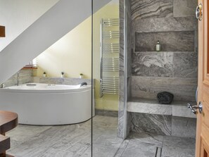 A modern bathroom with a freestanding bathtub, a glass shower enclosure, and a marble-tiled floor.