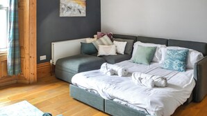 Ein modernes Schlafzimmer mit einer grauen Schlafcouch, einem Heizkörper und einem an der Wand befestigten abstrakten Gemälde.