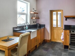 A compact kitchen with a sink, countertop, wooden cabinets, a window, and a door.