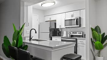 Une cuisine moderne avec des meubles blancs, un îlot central et un évier en acier inoxydable.