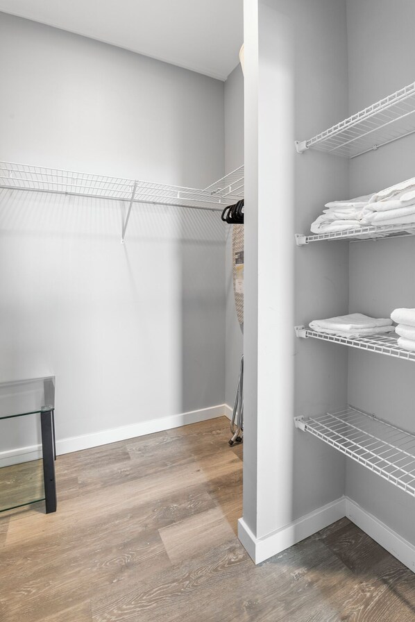 A walk-in closet with white shelving units and a metal drying rack.
