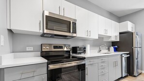 A modern kitchen with stainless steel appliances, grey cabinetry, and a white countertop. - Charming 1BR Near Encore f4pw (Everett)