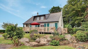 A house with a wooden deck, a red umbrella, and a stone wall in front. - The Villa in the country (PARIGNE)