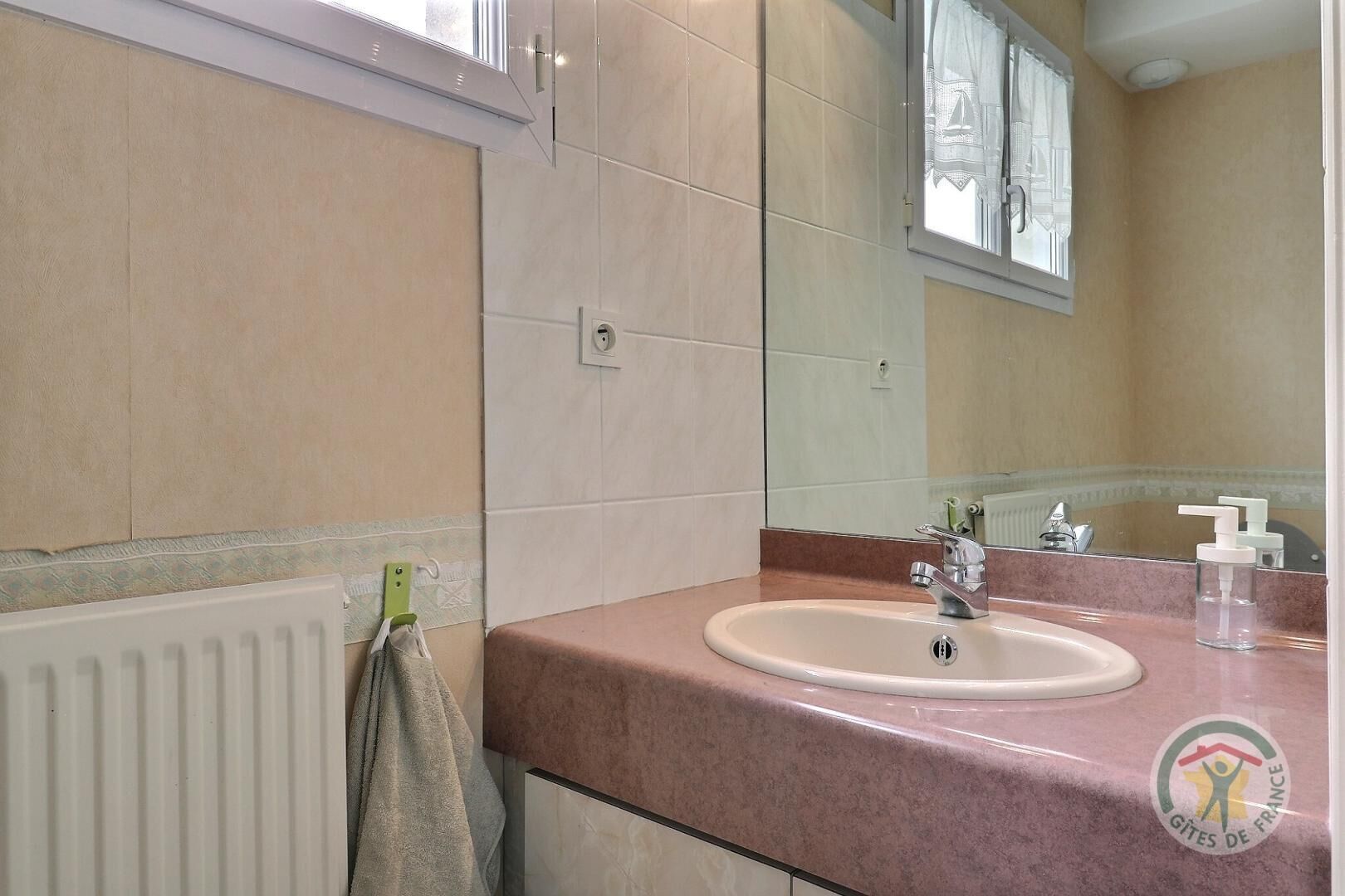 Een badkamer met een wastafel, spiegel en handdoekhouder.