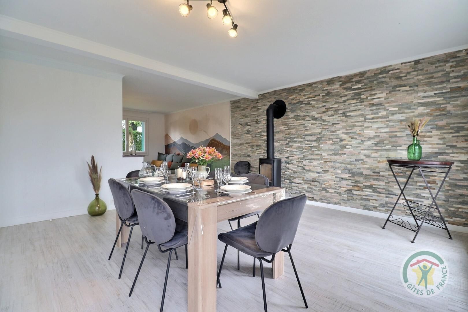 A modern dining area with a stone wall, a fireplace, and a table set for four.