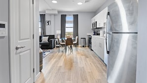 A modern kitchen with a stainless steel refrigerator, a dining area with a table and chairs, and a living room with a sofa and a view of the outdoors. - Charming 1BR Near Encore xphu (Everett)
