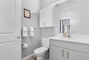 Moderni kylpyhuone, jossa on wc, pesuallas ja kaappeja.
