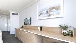 Ein Hotelzimmer mit einem Holztisch, einem gerahmten Bild und einer Pflanze.