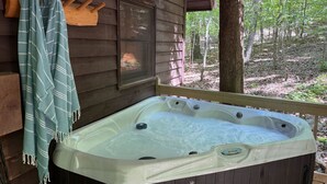 A hot tub in a wooden cabin with a view of the forest.