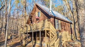 A wooden cabin with a balcony, a chimney, and a flag.