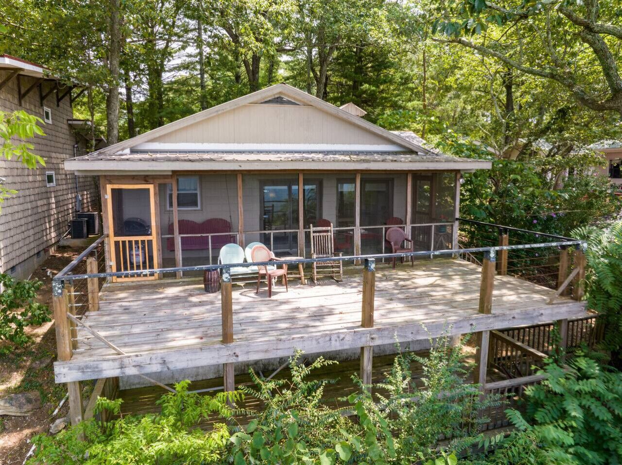 A cabin with a wooden deck, a covered porch, and a small outdoor seating area.