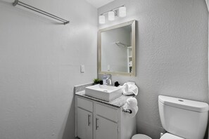 Ein Badezimmer mit Waschbecken, Spiegel, Handtuch und Toilette.