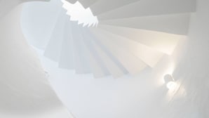 Un escalier en colimaçon avec un luminaire à sa base.
