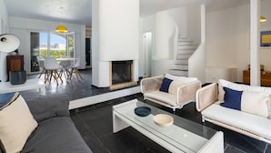 Un salon moderne avec une cheminée, des canapés blancs et une table basse en verre.