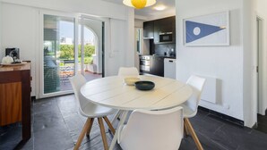 Une cuisine moderne avec des meubles de couleur sombre, une table à manger blanche et un luminaire suspendu jaune.