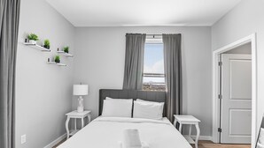 Habitación de hotel moderna con una cama grande, mesitas de noche, una lámpara y vistas a un puente por la ventana.