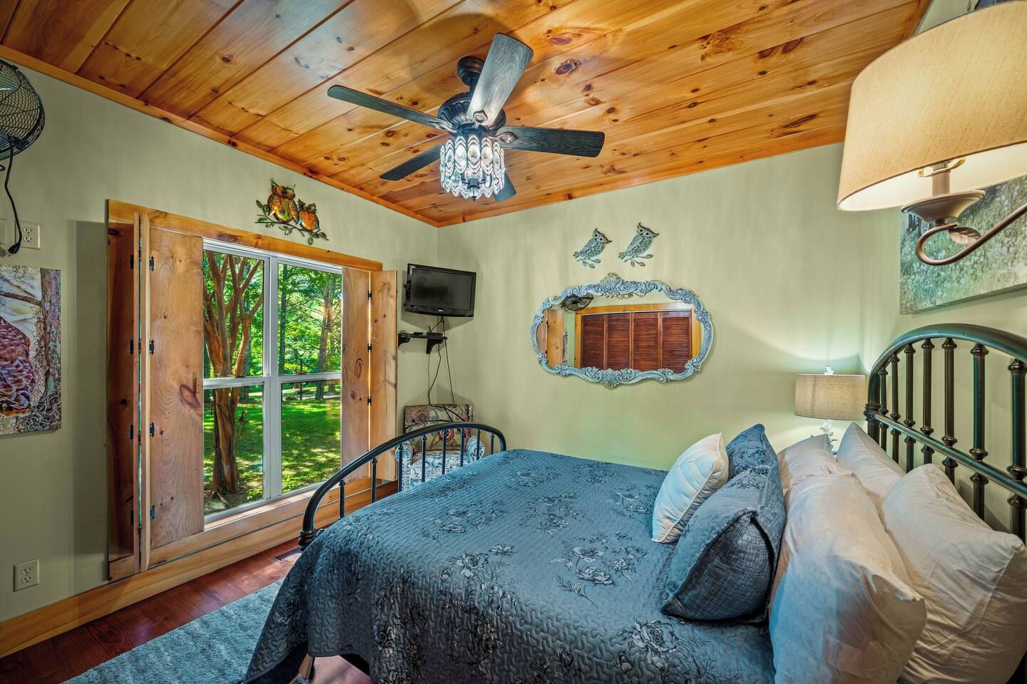 Une chambre à coucher avec un lit, un ventilateur de plafond, une fenêtre et un miroir.