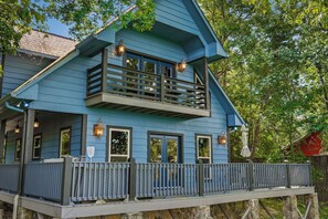 A two-story house with a balcony, a wooden deck, and a red-roofed structure in the background. - Paradise Found - Lookout Mt Edge, Hot Tub & Views (Mentone)