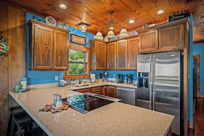 A kitchen with wooden cabinets, a stainless steel refrigerator, granite countertops, and a built-in stove. - Paradise Found - Lookout Mt Edge, Hot Tub & Views (Mentone)